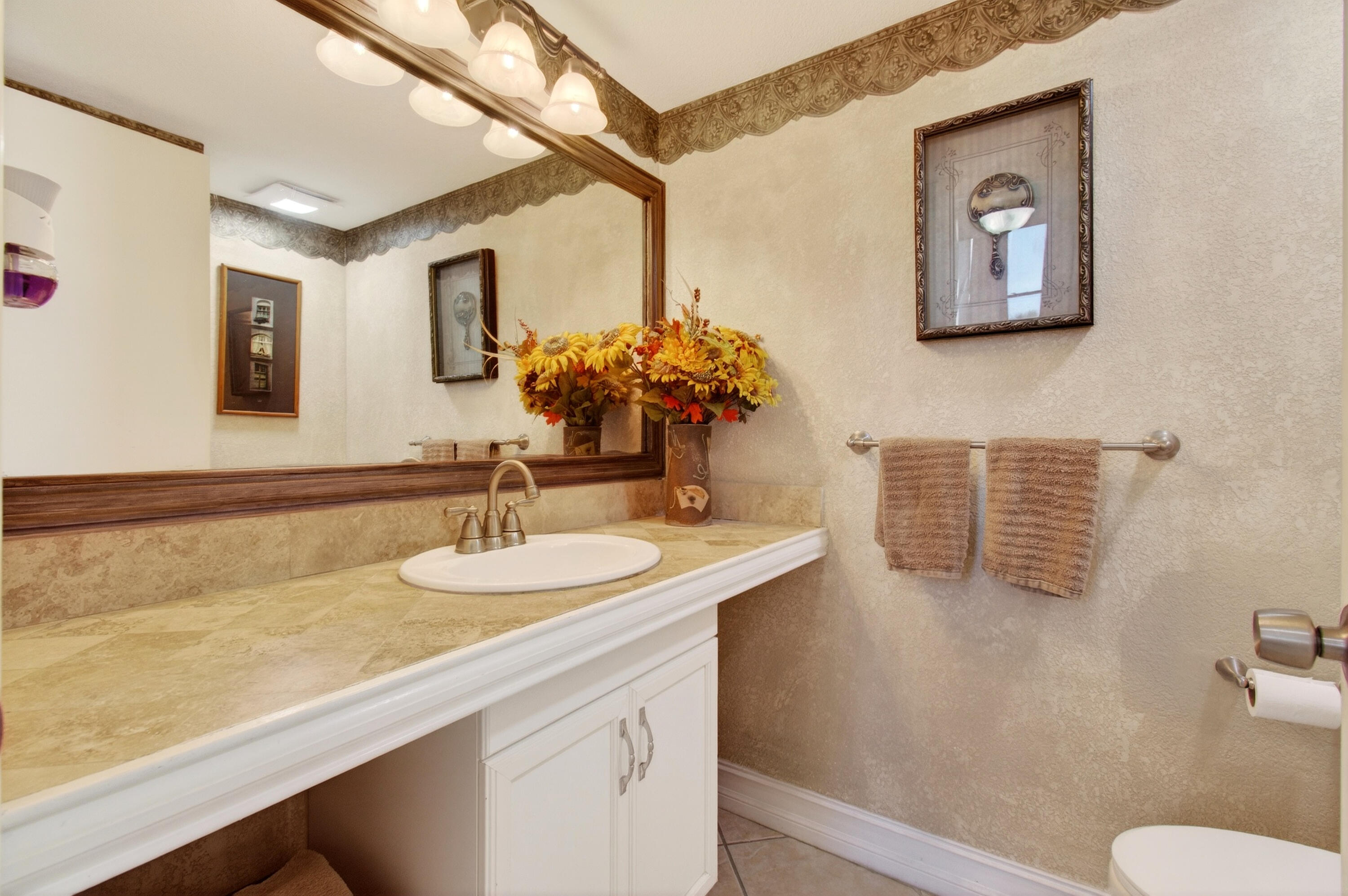 2303 Bridgewood Drive, Unit 2303 Boca Raton, FL 33434 - Photo 22 of 45 a bathroom with a granite countertop sink a mirror and a toilet