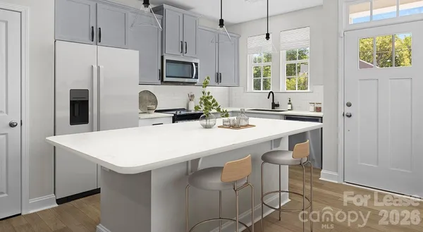 a kitchen with stainless steel appliances a sink a stove a refrigerator with a dining table and chairs