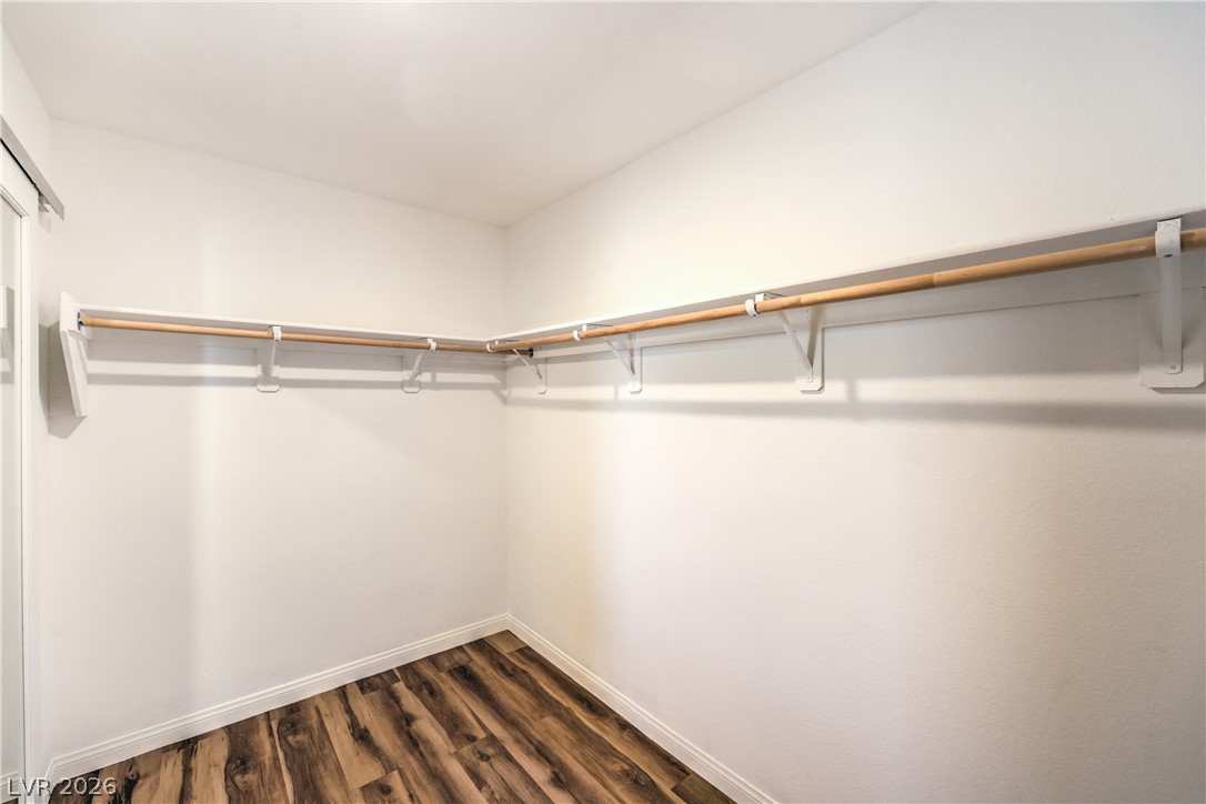 12103 Mojave Gold Road, Unit 4 Las Vegas, NV 89183 - Photo 11 of 23 A spacious walk-in closet boasts continuous wood hanging rods above clean wood-look flooring.