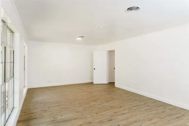 an empty room with windows fireplace and wooden floor