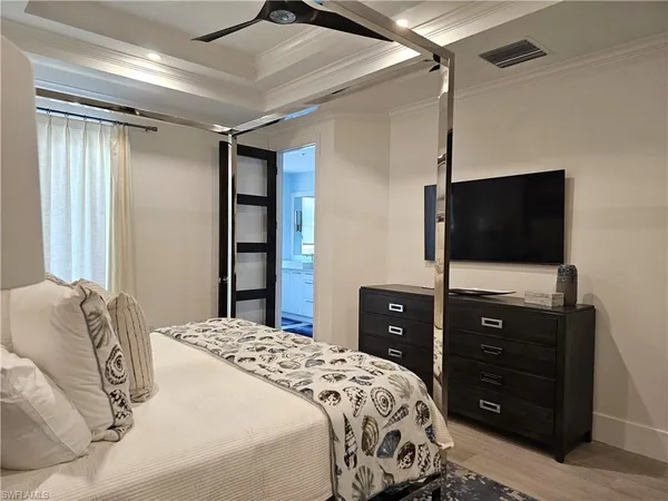 a bedroom with a bed and a flat tv screen on dresser