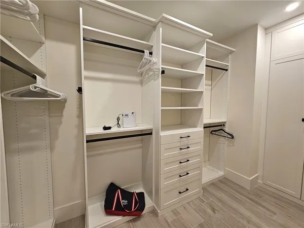 a view of walk in closet with clothes and shoes
