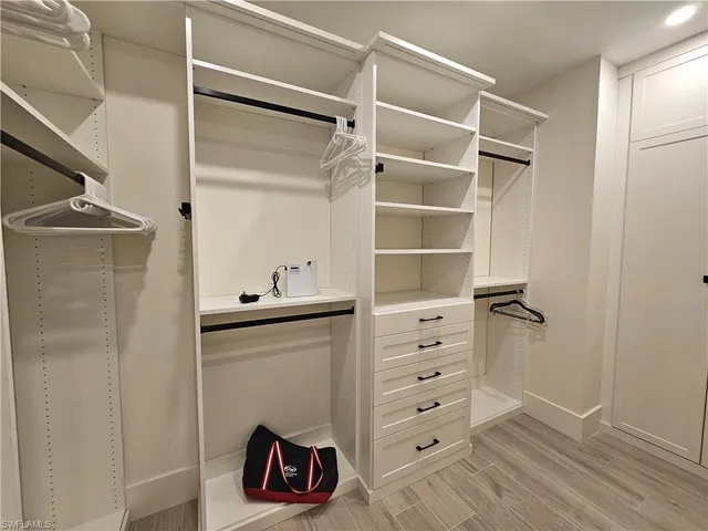 a view of walk in closet with clothes and shoes