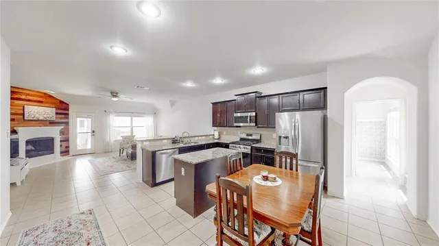 a kitchen with stainless steel appliances granite countertop a stove top oven a sink a dining table and chairs