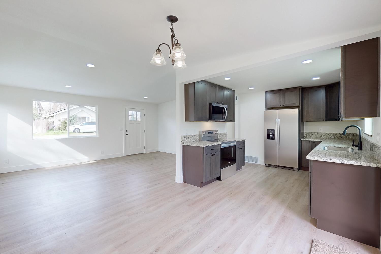 2441 Madrone Street Sutter, CA 95982 - Photo 12 of 47 a large kitchen with stainless steel appliances kitchen island granite countertop a stove top oven a sink dishwasher and a refrigerator with wooden floor