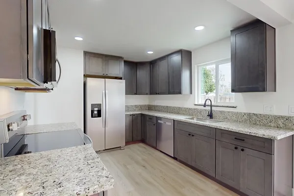 a kitchen with stainless steel appliances granite countertop a sink refrigerator and cabinets