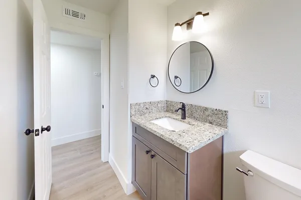 a bathroom with a granite countertop sink and a mirror