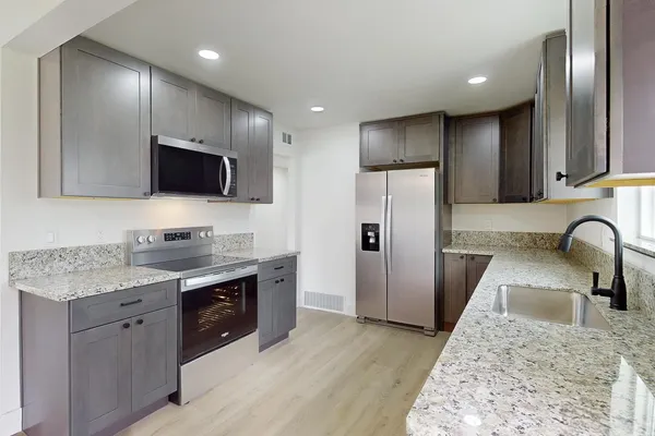 a kitchen with stainless steel appliances granite countertop a sink a stove a refrigerator and a microwave