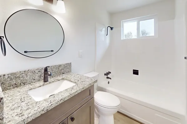 a bathroom with a granite countertop sink a toilet and a mirror