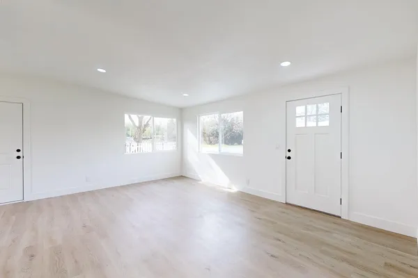 an empty room with wooden floor and windows