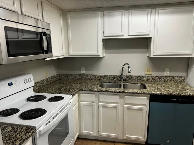 a kitchen with granite countertop white cabinets and white appliances