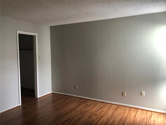 a view of an empty room with wooden floor and closet