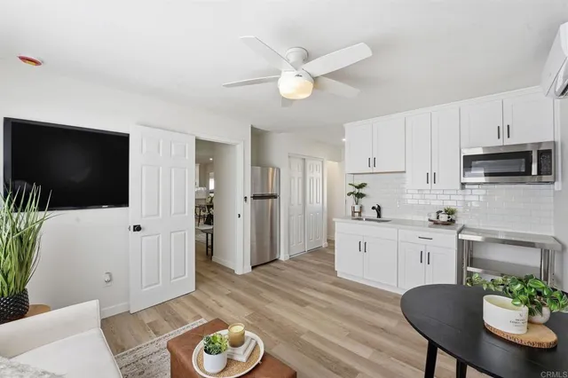 a kitchen with stainless steel appliances granite countertop a refrigerator a stove a sink dishwasher and white cabinets with wooden floor