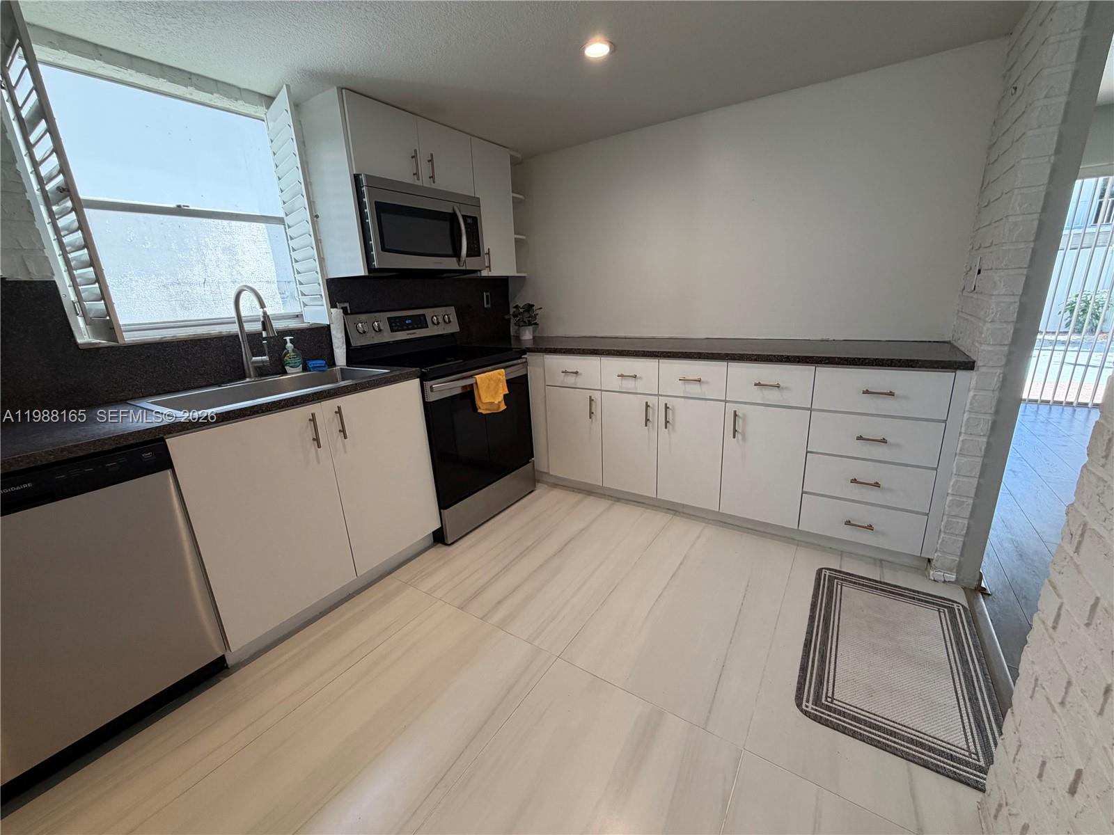 6760 Southwest 40th Street, Unit 41 Davie, FL 33314 - Photo 12 of 51 a kitchen with granite countertop white cabinets sink and stainless steel appliances