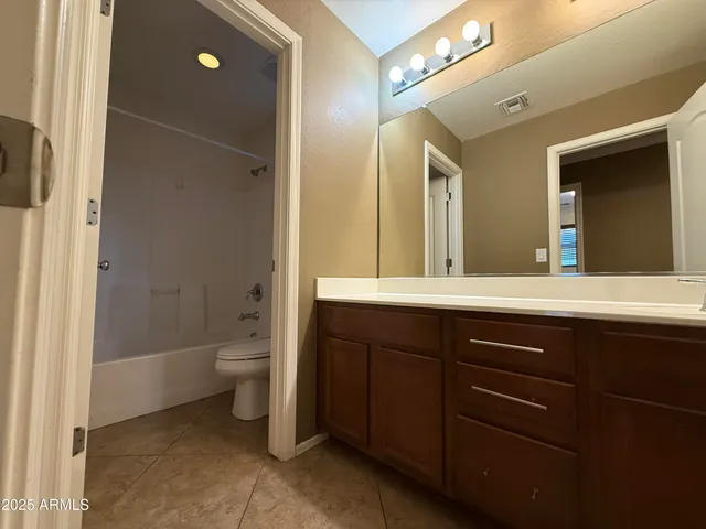 a bathroom with a granite countertop sink a toilet and a mirror