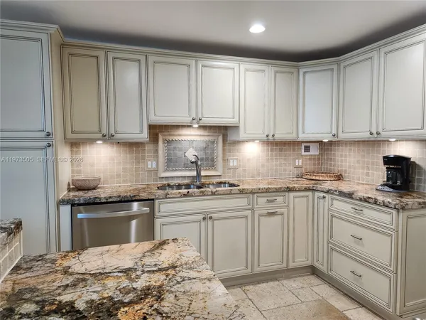 a kitchen with white cabinets granite counter tops and a stove