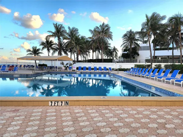 a view of swimming pool with a yard and palm trees