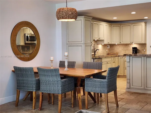 a kitchen with stainless steel appliances granite countertop a dining table chairs and a refrigerator