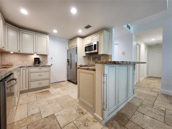 a kitchen with stainless steel appliances granite countertop a refrigerator and a stove top oven