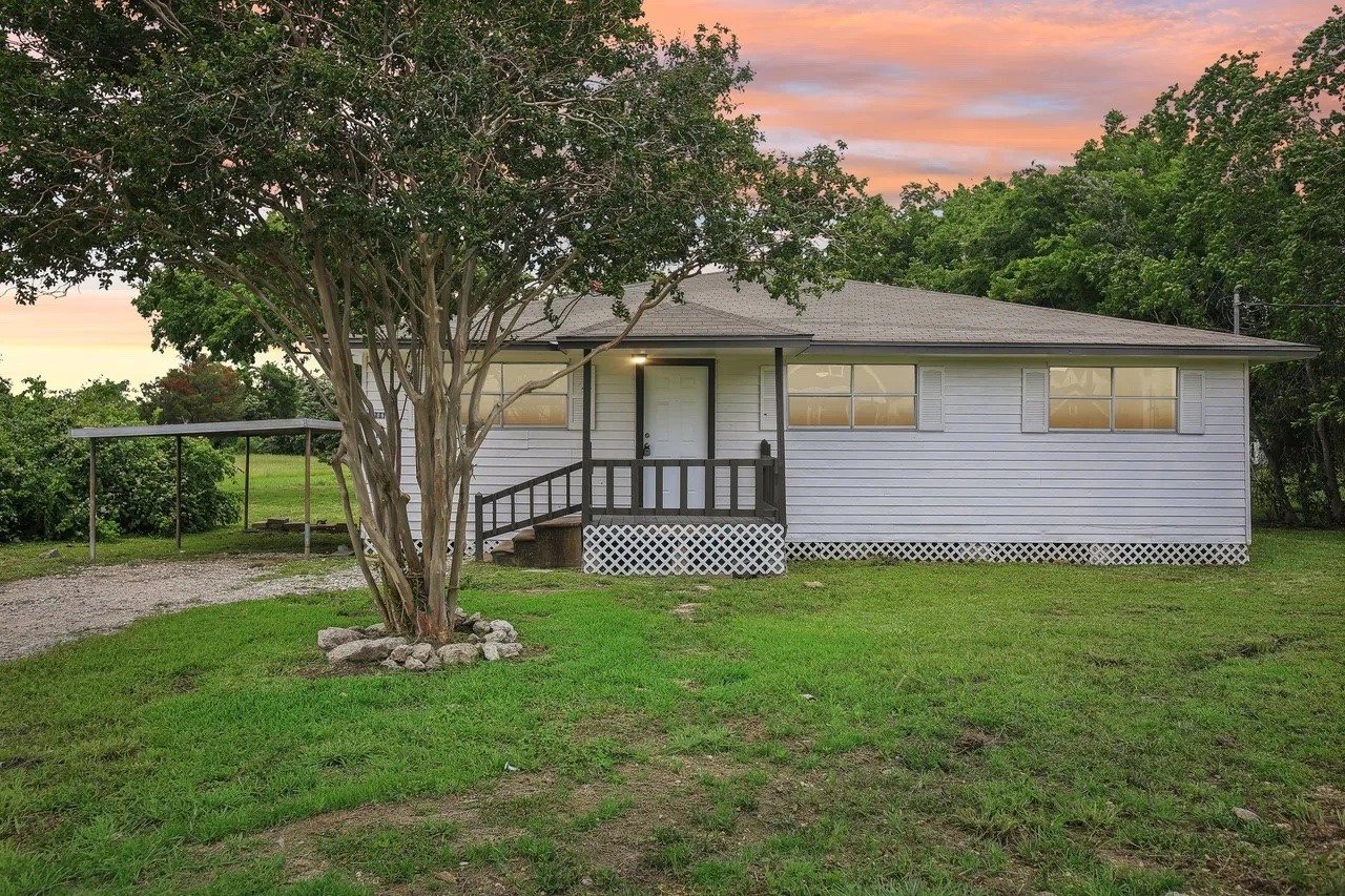 a front view of a house with a garden and trees