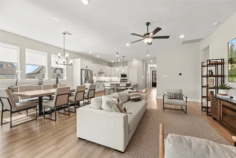 a living room with furniture kitchen view and a chandelier