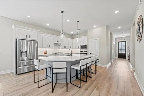 a kitchen with stainless steel appliances kitchen island granite countertop a table chairs sink and wooden floor