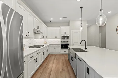 a large kitchen with stainless steel appliances lots of counter space wooden floor and stove