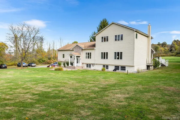 a view of white house with a big yard and large trees