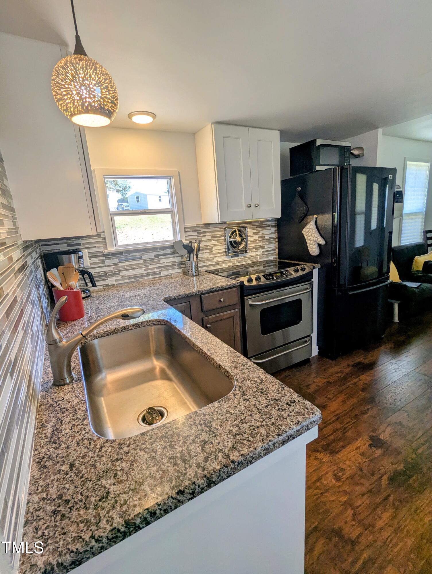 529 Flanagan Road Henderson, NC 27537 - Photo 12 of 38 a kitchen with stainless steel appliances granite countertop a sink a stove and a wooden floors