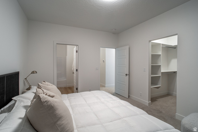 2768 Becco Trail, Unit 63 St. George, UT 84770 - Photo 13 of 27 Bedroom featuring a walk in closet, light carpet, and connected bathroom