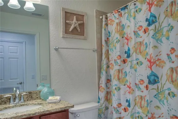 a bathroom with a granite countertop sink a mirror and a shower curtain