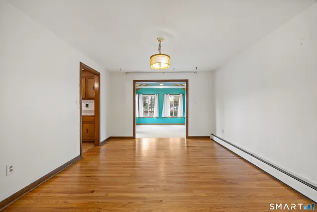 a view of an empty room with window and wooden floor