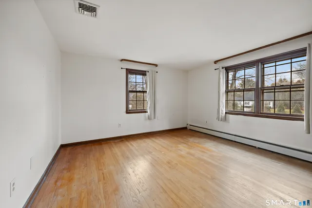 an empty room with wooden floor and windows