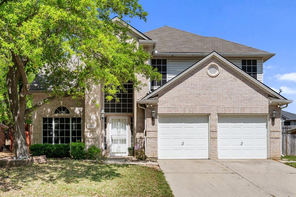Traditional home featuring concrete driveway, brick siding, and an attached garage