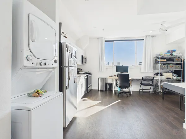a living room with furniture a dining table and a refrigerator
