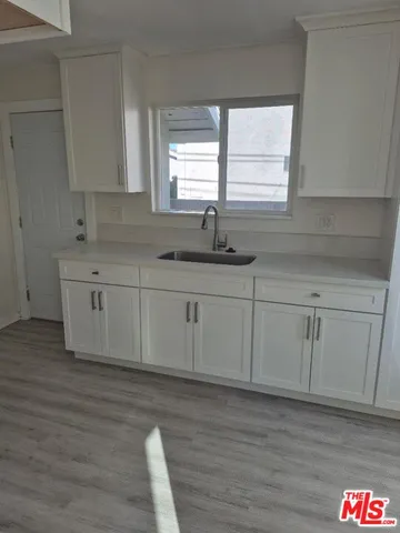 a kitchen with granite countertop white cabinets white appliances a sink and a window
