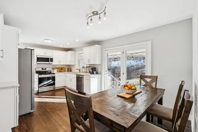 a open dining room with stainless steel appliances a dining table and chairs
