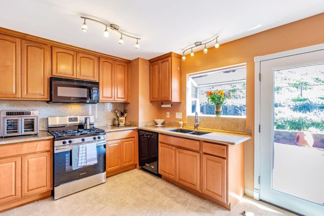 a kitchen with stainless steel appliances granite countertop wooden cabinets a sink and a stove