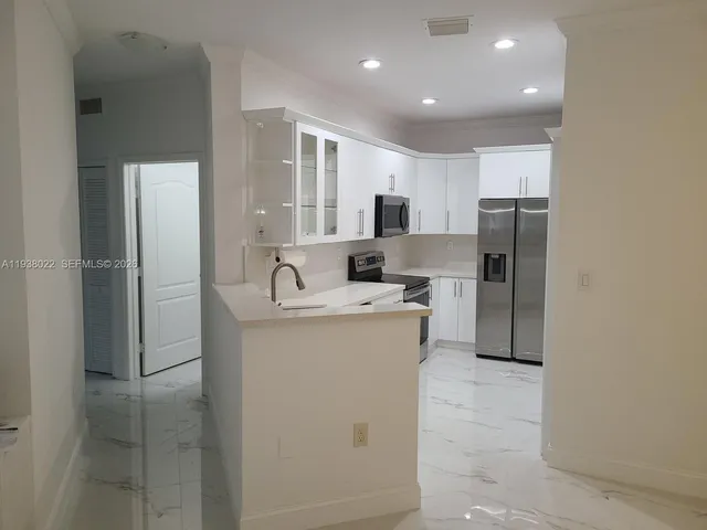 a kitchen that has a refrigerator a sink and white cabinets