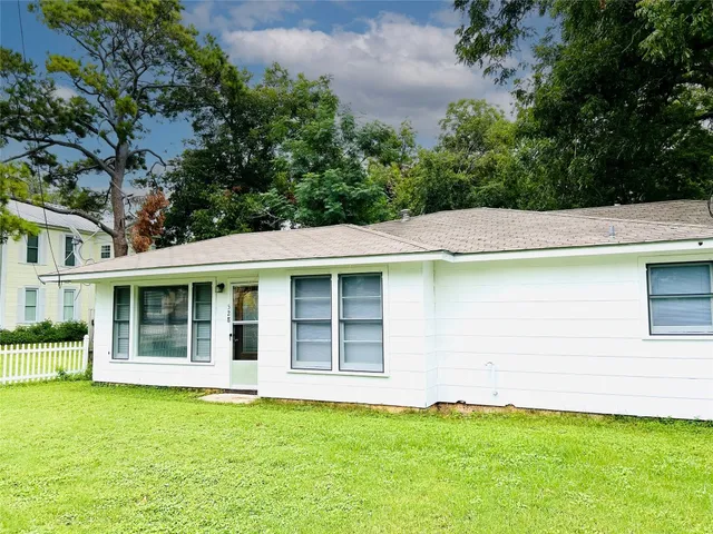 a backyard of a house with large trees and plants