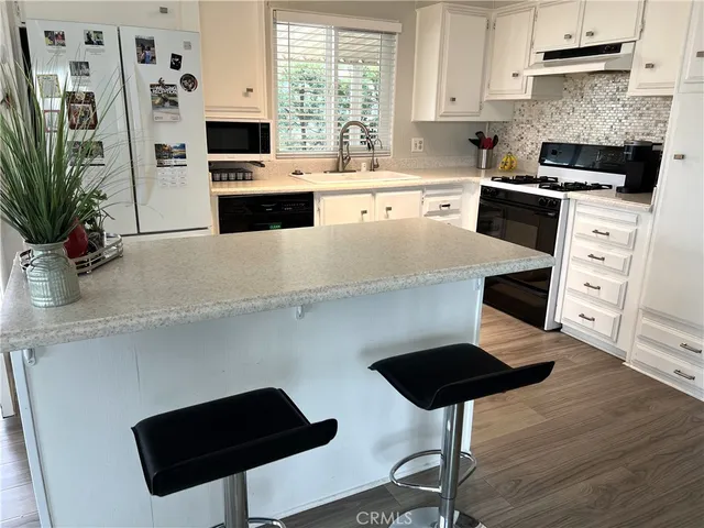 a kitchen with stainless steel appliances a stove a sink a microwave a refrigerator a stove and white cabinets