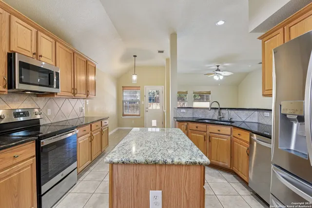 a large kitchen with granite countertop a large counter top stainless steel appliances and cabinets