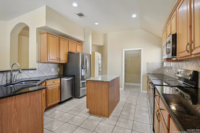 a kitchen with stainless steel appliances granite countertop a refrigerator a sink a stove and island