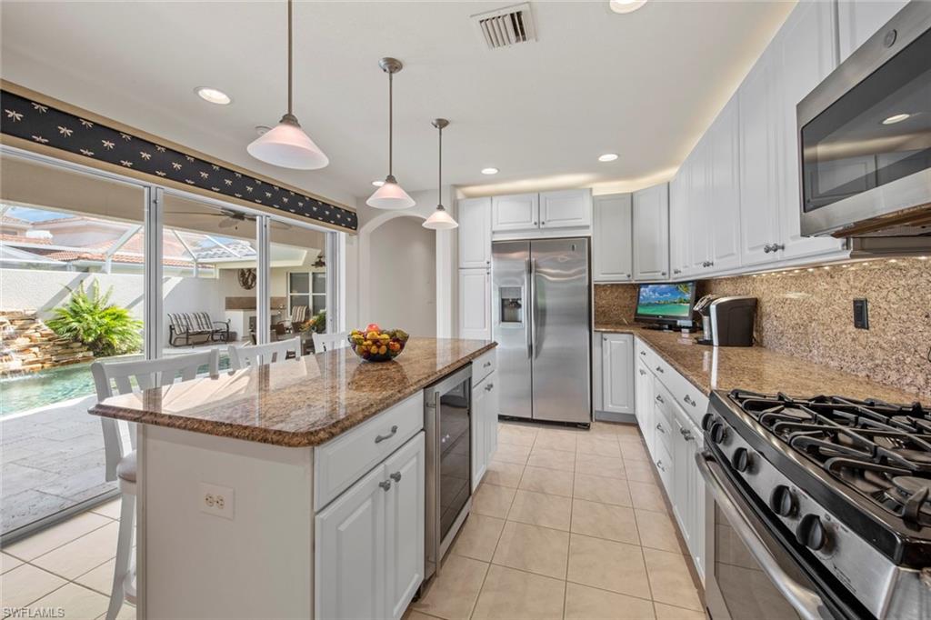 9046 Astonia Way Estero, FL 33967 - Photo 21 of 47 a kitchen with stainless steel appliances granite countertop a sink a stove and a wooden floors