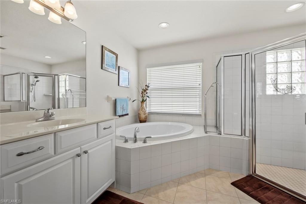 9046 Astonia Way Estero, FL 33967 - Photo 26 of 47 a bathroom with a double vanity sink a mirror and a bathtub