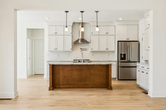 a large kitchen with stainless steel appliances granite countertop a stove a refrigerator and a microwave oven with white cabinets