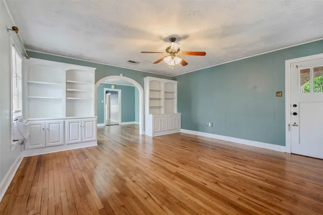 a view of an empty room with wooden floor and a window