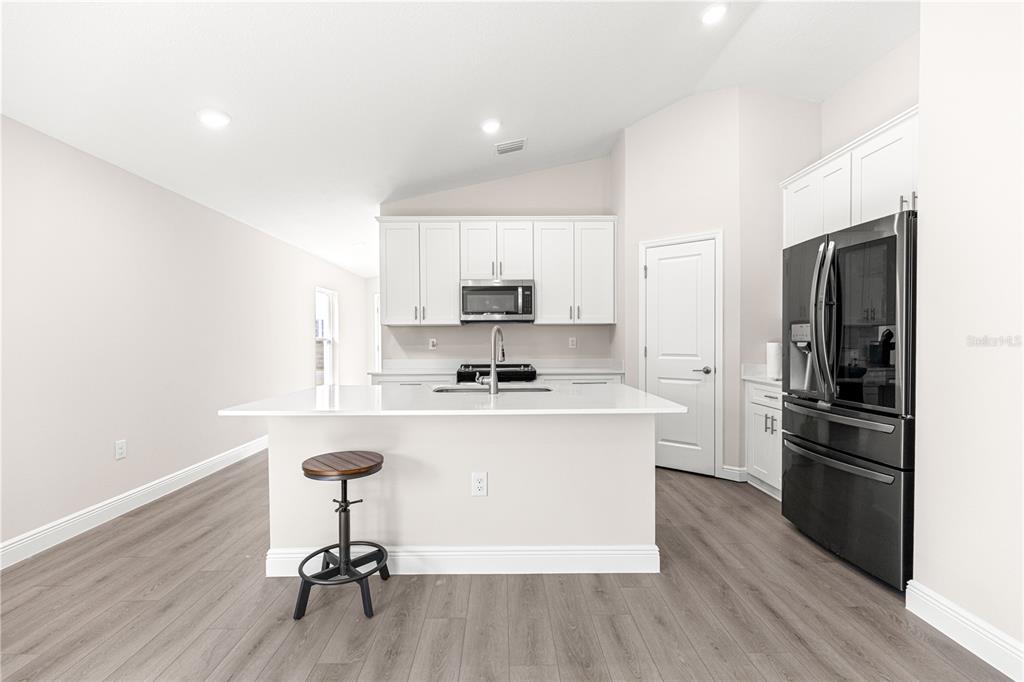 9611 Southwest 62nd Court Ocala, FL 34476 - Photo 7 of 41 a kitchen with a refrigerator a stove a sink and a dining table with wooden floor