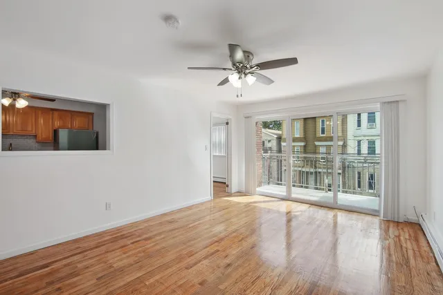 a view of an empty room with a window and wooden floor