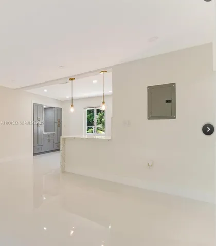 an empty room with windows and refrigerator